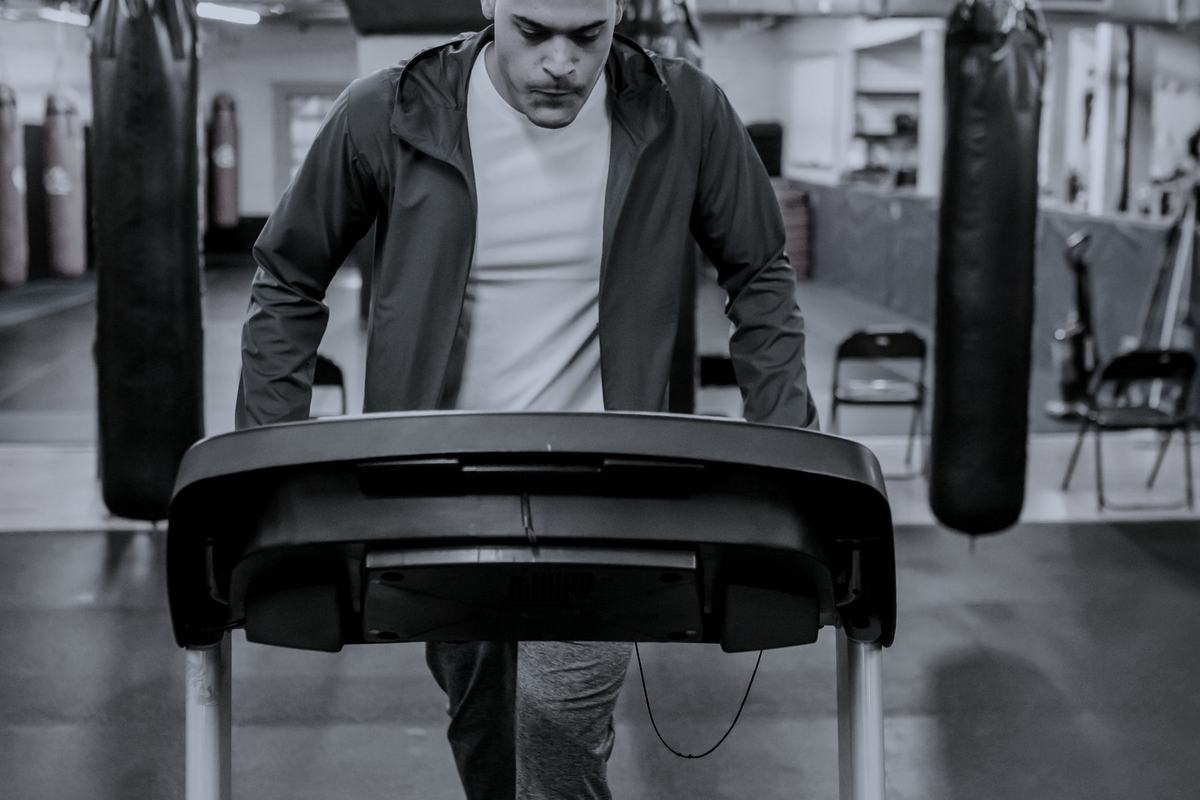 A man walking on a treadmill in a gym, seen from the front.