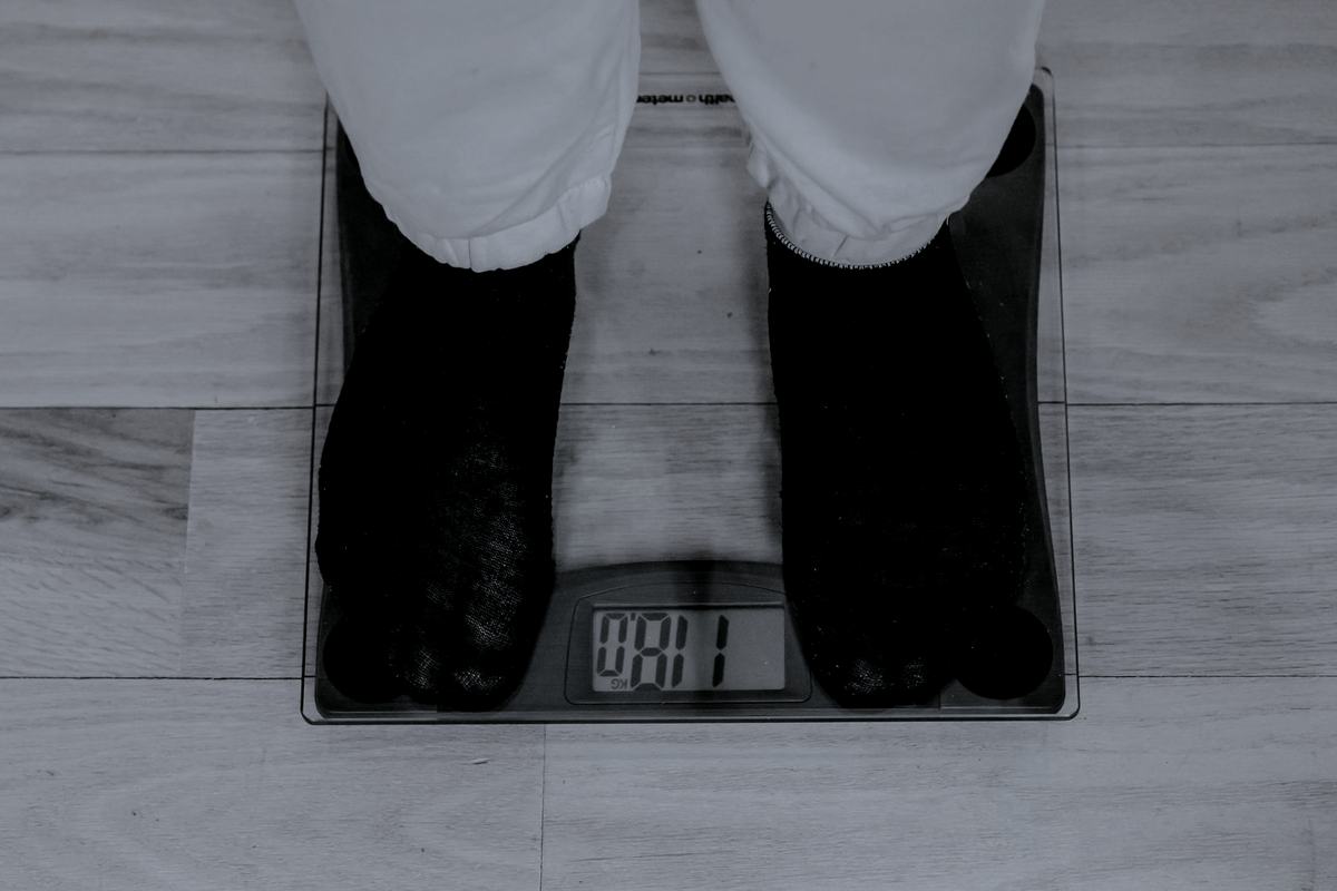 Bare feet on a digital bathroom scale on a wooden floor.