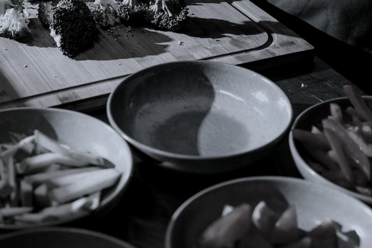 A cook chopping broccoli on a board surrounded by fresh vegetables.