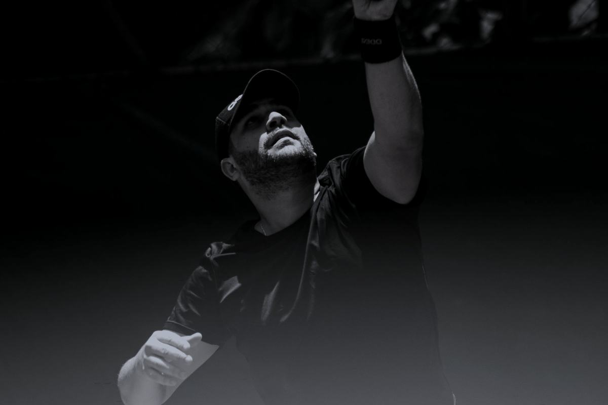 A tennis player at the top of a serve on an outdoor court.
