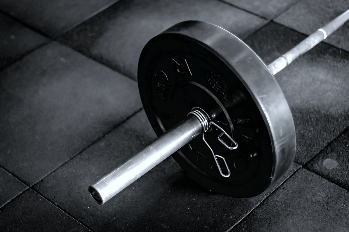 A loaded barbell resting on a dark rubber gym floor.