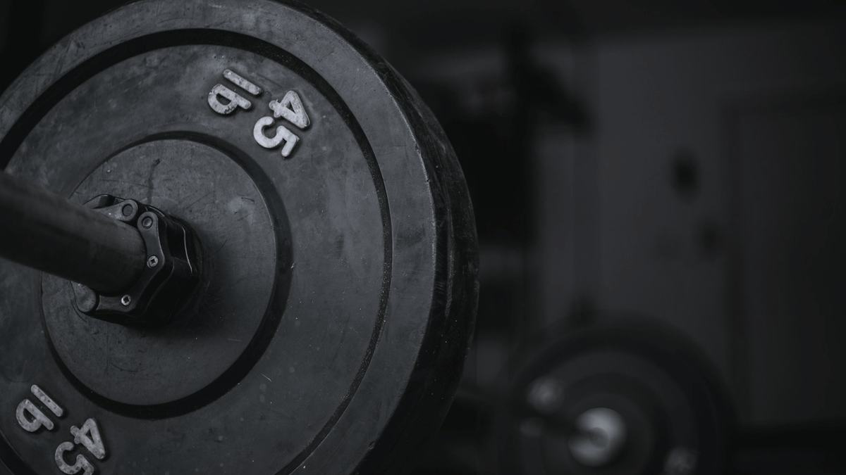 A 45 lb plate on a loaded barbell, shot close in near-monochrome.