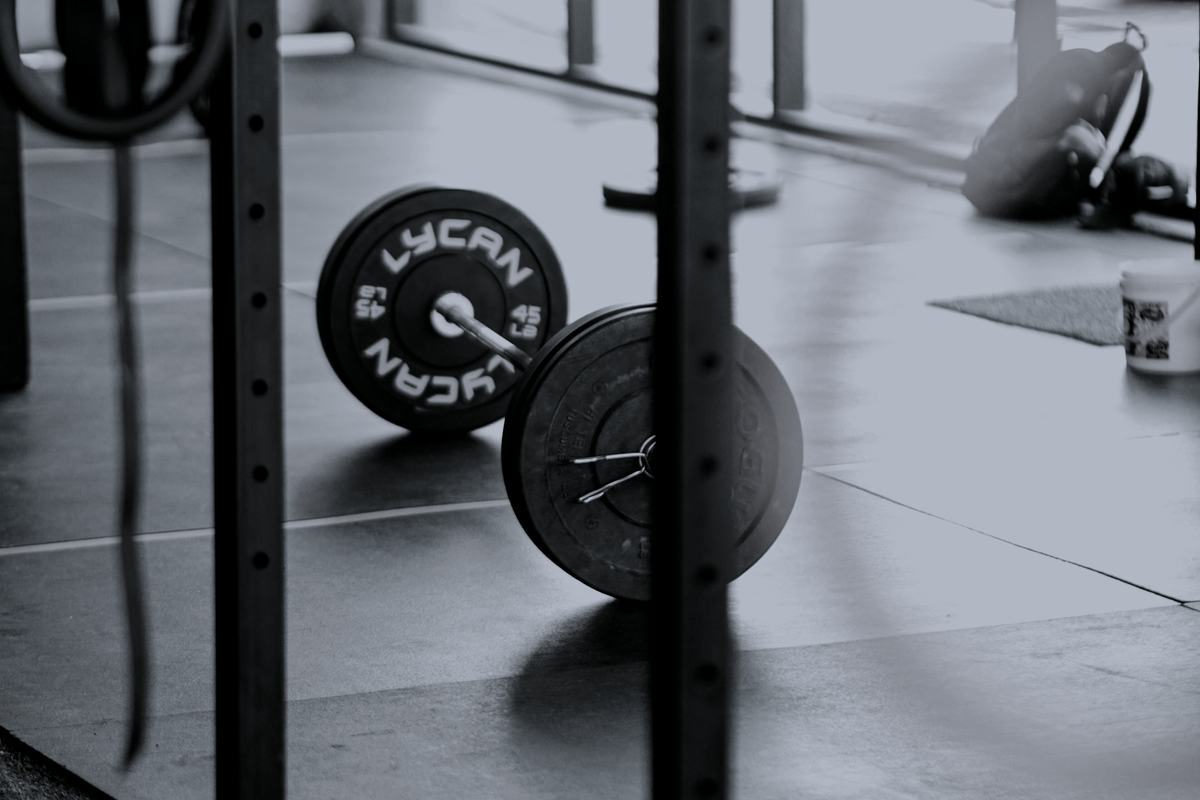 A single loaded barbell on the floor of a bright, empty gym.