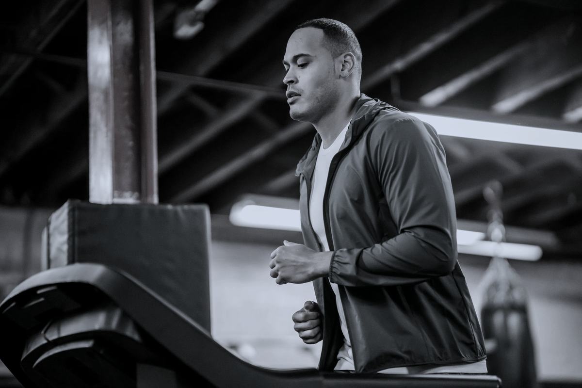A man jogging on a treadmill in a gym, seen from the side.