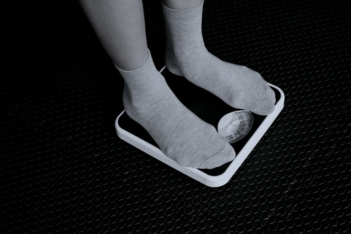 Feet in socks standing on a bathroom scale, seen from above.