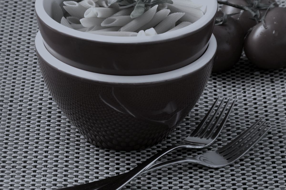 Penne pasta in bowls with basil and tomato.