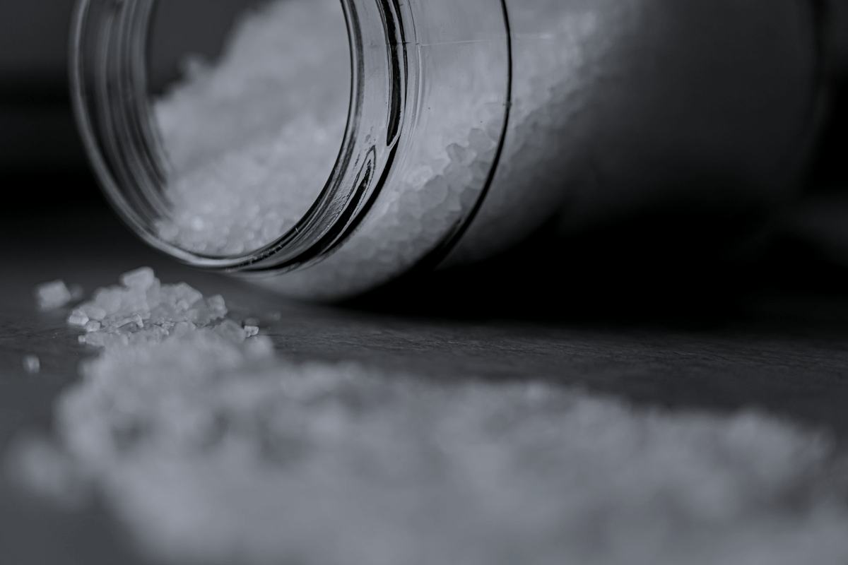 Coarse rock salt spilling from a glass jar.