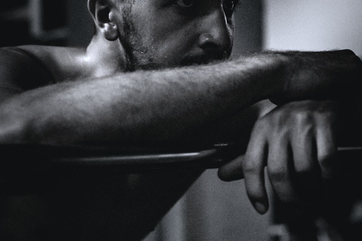A lifter leaning on a loaded barbell in a dimly lit gym.