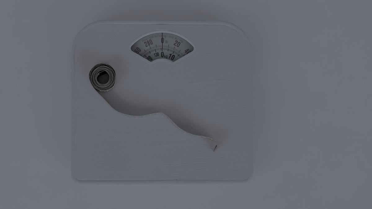 A pair of floor scales beside a coiled measuring tape.